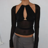 Black long-sleeve top with cut-out design worn by a person on a plain background